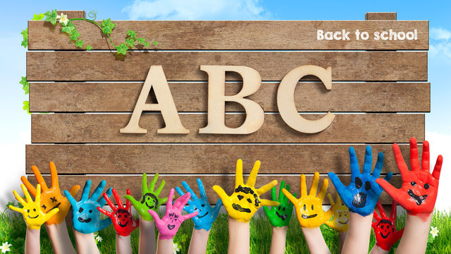 in bunten Farben angemalte Kinderhände und Schild mit "ABC - Back to school"