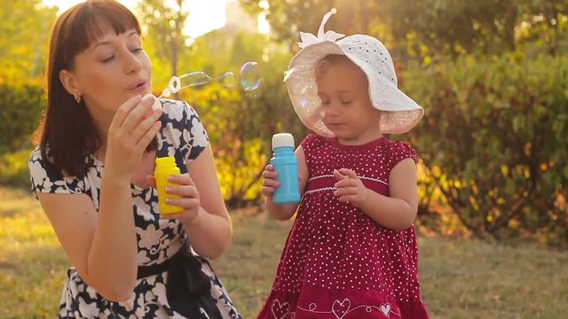 A little girl with her mom blowing bubbles and having fun