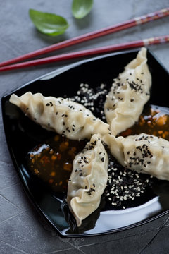 Close-up of steamed korean dumplings served with sesame seeds and dipping sauce, selective focus