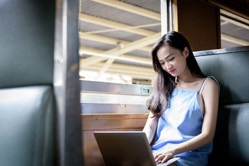 Fototapeta na wymiar Asian woman traveler has working with laptop inside the train at Hua Lamphong station at Bangkok, Thailand.