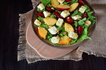 Fruit salad with arugula, plums, nectarines and soft cheese on a plate