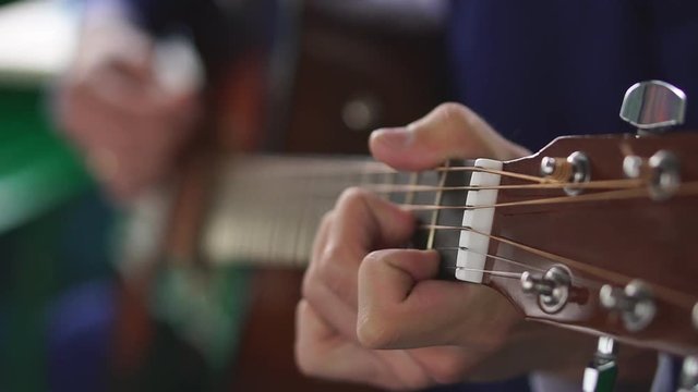 Man's hands playing acoustic guitar, close up
