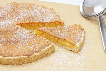 Slice of homemade coconut lemon tart on baking paper.
