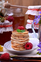 Stack of pancakes decorated with raspberry and mint on a white plate. Village style