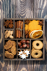 wooden box with Christmas sweets and spices on wooden background, vertical top view