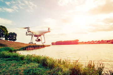 quadcopter drone flying with a camera over a lake.