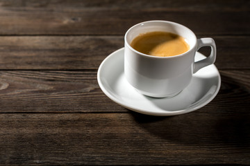 Black coffee in white cup on black wood background