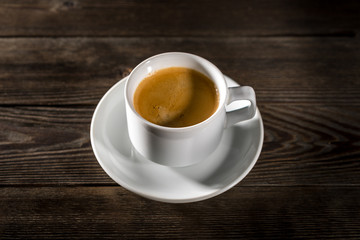 Black coffee in white cup on black wood background