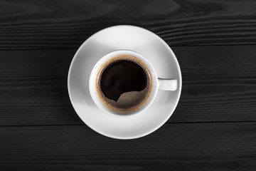 Black coffee in white cup on black wood background