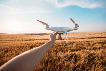 Fototapeta premium the white drone in hands at the man isolated against the background of the yellow field