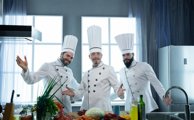 Three cheerful cooks in the kitchen in the restaurant