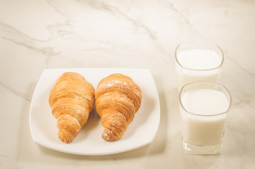breakfast with croissants and milk/croissants in a white plate and two glasses milk on a white background. Selective focus