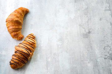 freshly baked croissant decorated with chocolate sauce isolated on a gray slate background. Top view with copy space