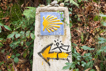 Symbol of the Way of Saint James, or Camino de Santiago, with a yellow shell and a yellow arrow with a man on it