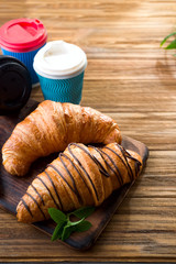cups of coffee and two croissants on the street in Croissant Cafe. Inscripton on cup - Croissant Cafe. Breakfast to go