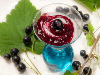 Homemade black currant jam with yogurt in a glass on a table