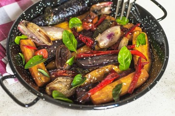 Baked sliced vegetable on black pan.