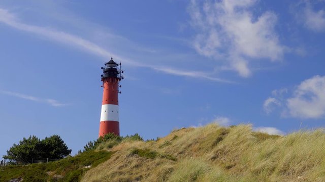 Wundersch&ouml;ner Leuchtturm H&ouml;rnum Sylt mit D&uuml;nen Landschaft  und blauen Himmel
