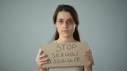 Bruised woman holding stop sexual assault sign, female rights protection