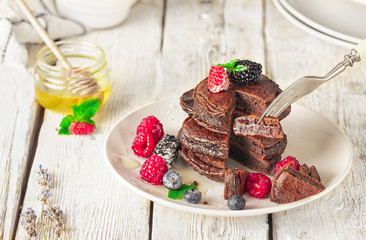 Chocolate pancakes with fresh berries, honey and mint