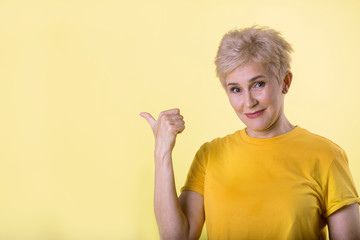 beautiful stylish woman with a short hairstyle on a yellow background with a gesture of hands