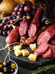 Salami sliced in rustic style. Salami sausage. Different sausages with cheese, grapes and olive