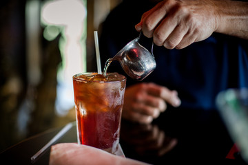 Person pouring flavor into iced team glass.