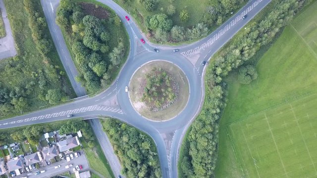 Top down aerial view of cars using a traffic roundabout in an urban UK town