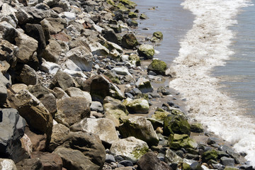 A view of Malibu beach, with stones and rocks and Pacific ocean in summer time in California
