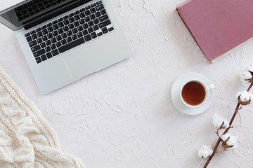 top view of old book, smart phone, cup of tea, cotton branch on concrete background, flat lay. Autumn or winter concept