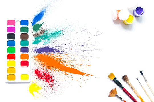 Colorful paints and brushes with multi-colored spray splash paint, gouache, watercolor isolated on white background. A spray of colored paints from a set for drawing. 