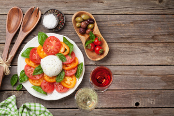 Caprese salad with tomatoes, basil and mozzarella with wine