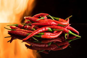 Hot chilli with burning fire on black surface