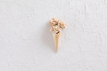 Top view of still life flowers on waffle cone on white texture background, flat lay.