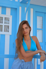 atractiva mujer joven con bikini azul con el fondo de una casa  pescadores con rayas azules y...