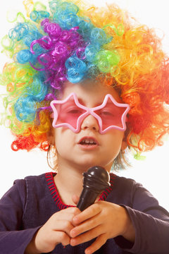 The famous actress. Humorous photo of cute child girl singing with a microphone (Happy childhood, teaching singing, music, child development concept)