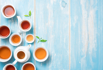 Tea concept,Teapot and cup of herbal tea with green tea leaves on blue table ,top view