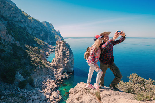 Young couple hikers taking selfie photo on phone in the mountains background the sea. Beautiful Man and Woman traveling active adventure vacations.