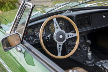 view into an green  oldtimer convertible car with a wooden steering wheel