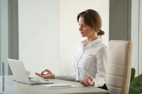 Calm Mindful Businesswoman Meditating At Office Desk With Eyes