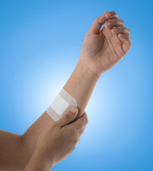 Plaster closed wound on the arm against blue background,Medical and healthcare concept.