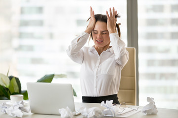 Emotional stressed businesswoman in nervous breakdown after overwork with laptop and crumpled...