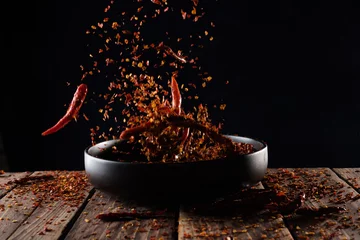 Keuken spatwand met foto Pouring cayenne pepper powder into the bowl on wood table,Motion blur © showcake