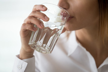 Dehydrated woman feeling thirsty holding glass drinking filtered pure mineral fresh water for body...