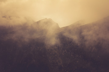 View of morning fog in the mountains. Misty landscape of rocky mountain slopes. Color toning and low contrast. Outdoor travel background.