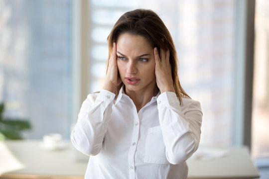 Stressed tired businesswoman in panic feeling fatigued frustrated, exhausted female employee or office worker suffering from overwork, headache, hormone imbalance, having migraine at work concept