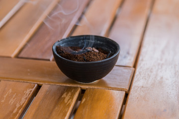 kohlendes Kaffeepulver in einer Schale auf einer Holzplatte