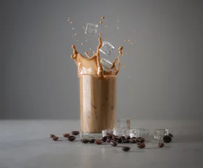Photo sur Plexiglas Milk-shake Iced coffee splash with ice cubes and beans against grey concrete