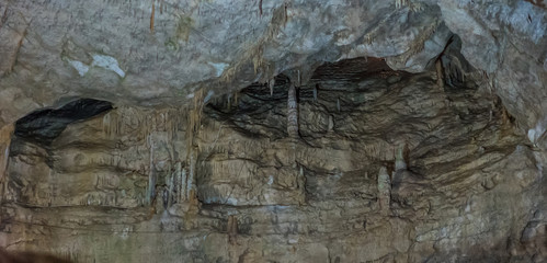 Under the ground. Beautiful view of stalactites and stalagmites in an underground cavern - New Athos Cave. Sacred ancient underworld formations.