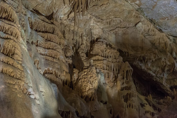 Under the ground. Beautiful view of stalactites and stalagmites in an underground cavern - New Athos Cave. Sacred ancient underworld formations.
